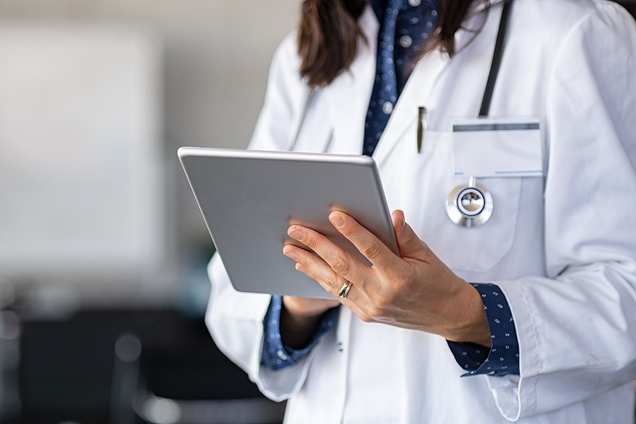 Close up of woman doctor hands using digital tablet at clinic. C