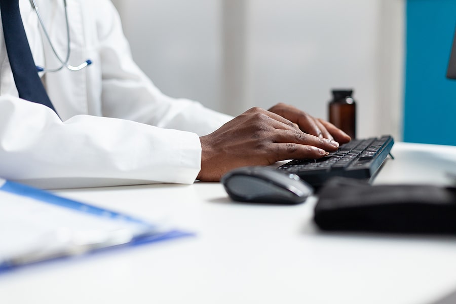 Closeup Of African American Doctor Typing Medicine Prescription Doctor typing on computer to represent revenue cycle management services provided by MedCycle Solutions to the Otsego, MN area